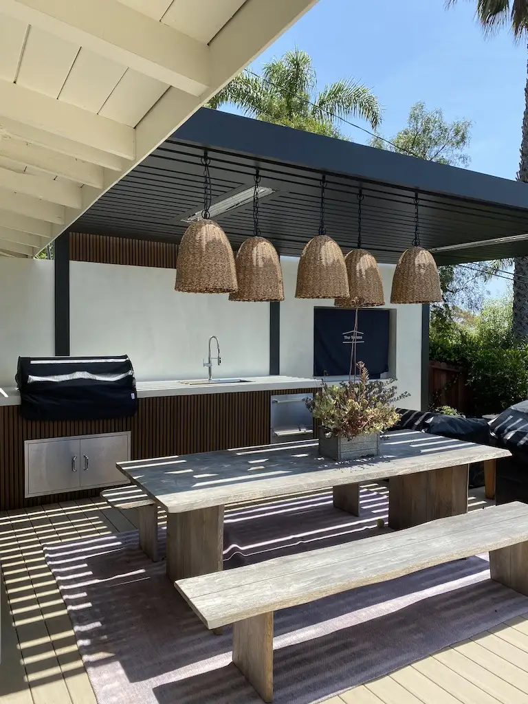 A modern outdoor kitchen in Malibu under a pergola. Depicts pergola trends in 2025.