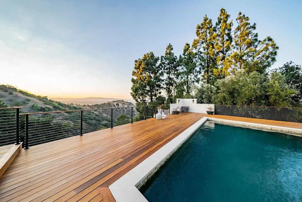 A wooden ipe deck and pool on a hillside in Studio City, California. Views of lush greenery and trees on the surrounding hills.